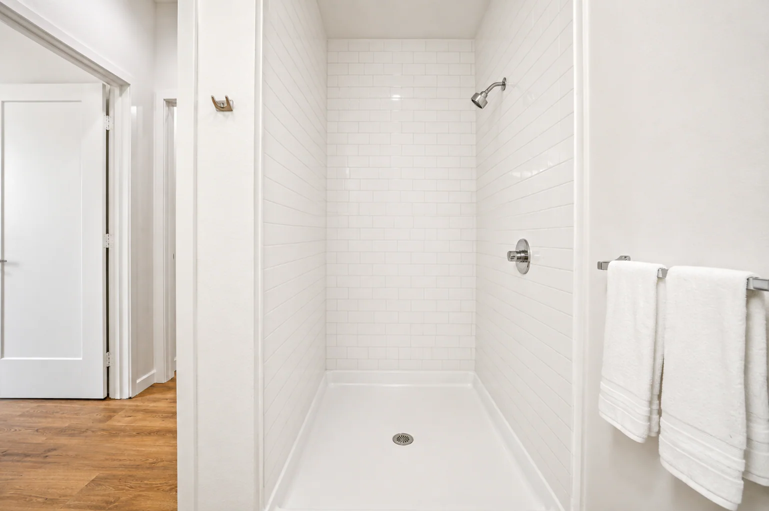 Walk-in shower with white subway tile and chrome fixtures